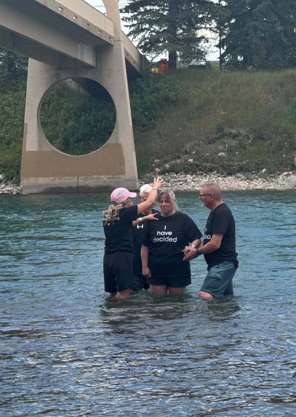 Valerie praying over a woman being baptized in a river