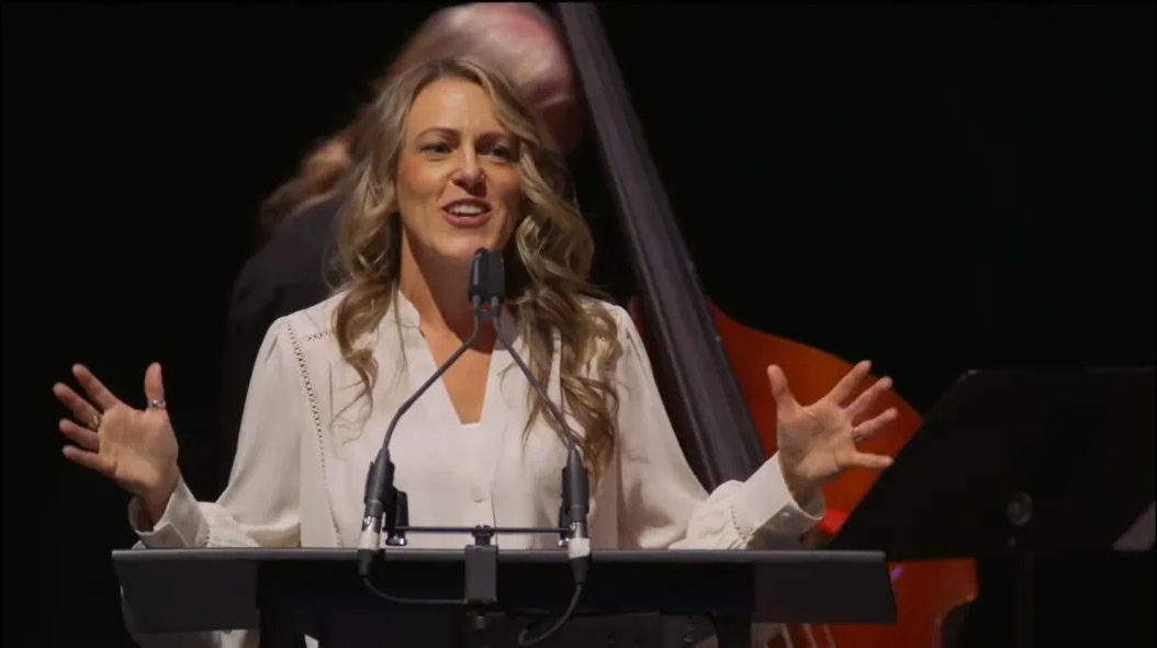 Valerie speaking at a podium on stage