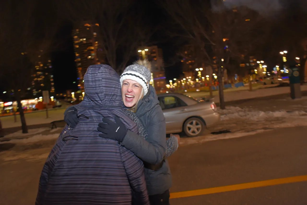 Valerie laughing and hugging someone on a winter night downtown