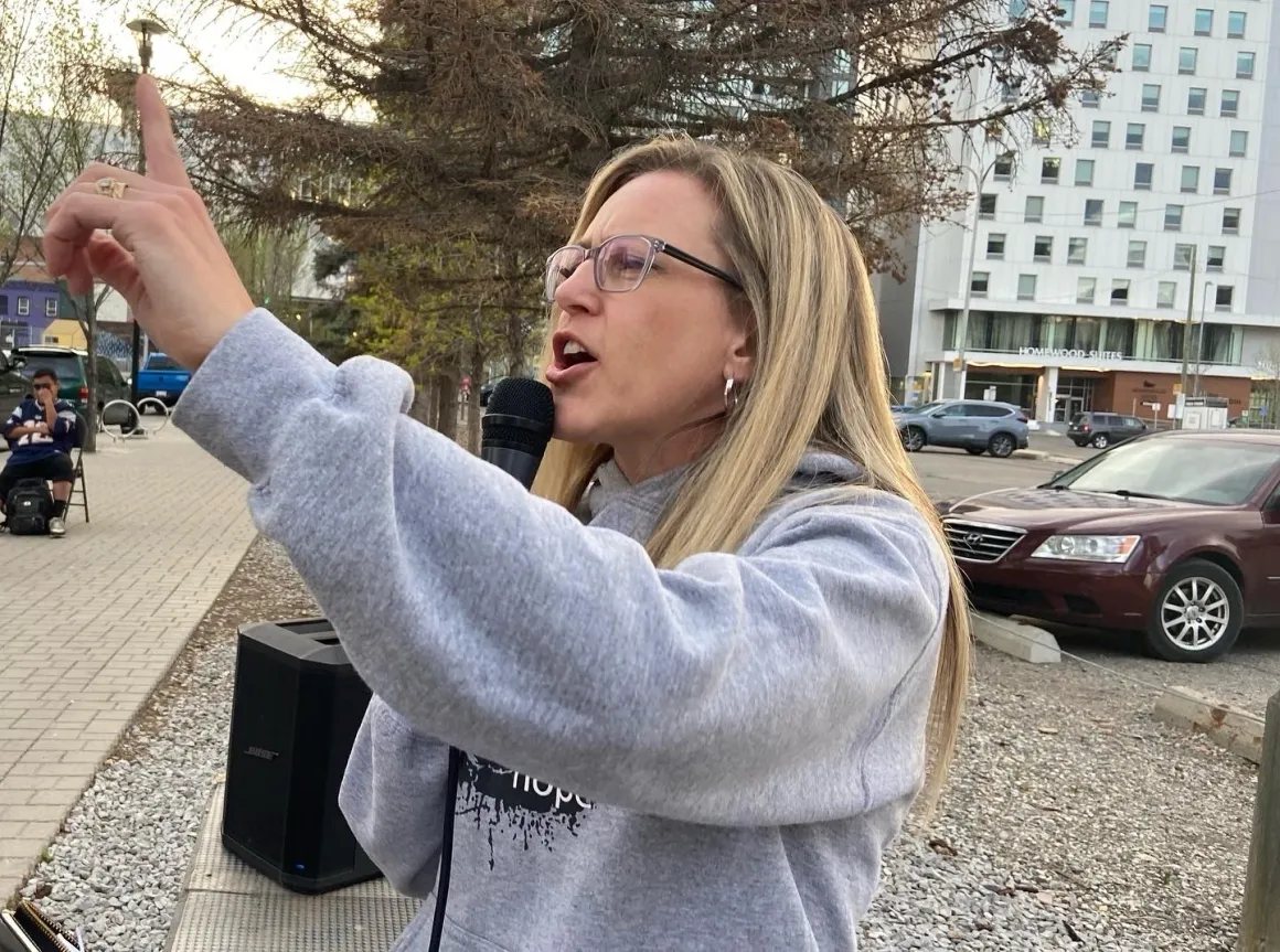 Valerie preaching with a microphone outdoors downtown